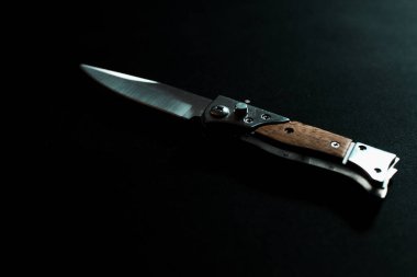 Koyu arkaplanda tahta saplı katlanmış bıçak.