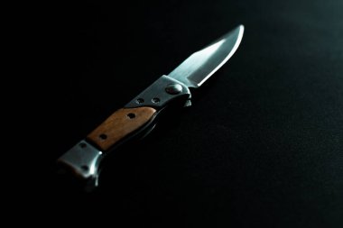 Koyu arkaplanda tahta saplı katlanmış bıçak.