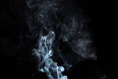 incense stick with white smoke against black background