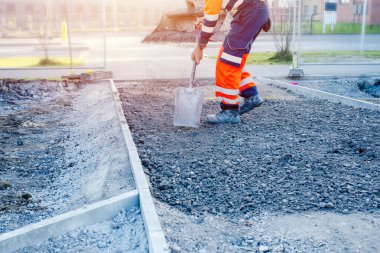 A new footpath is under construction as builders bring stone, levelling it and compacting
