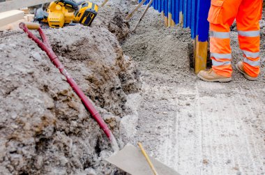 Builder installing rail slippers painted blue into semi-dry concrete to form a secure barrier around new school playground as part of extra safety measures