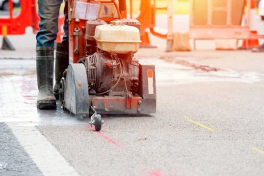 Close up and selective focus of the petrol powered road saw with dimond blade cutting asphalte road surface