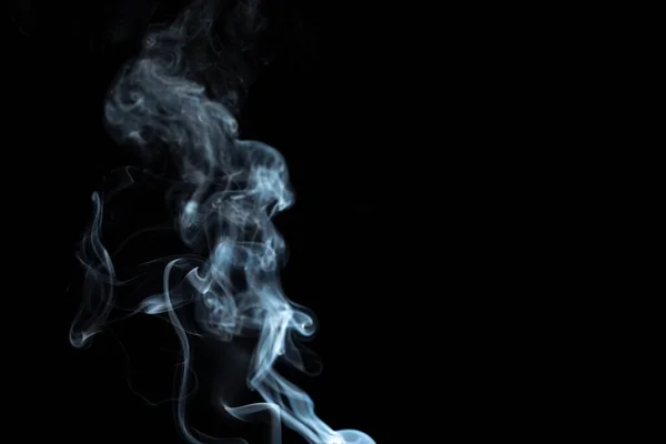 incense stick with white smoke against black background