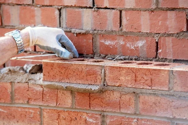 Close up of industrial bricklayer laying bricks on cement mix on construction site