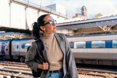 Traveler with a backpack waiting for a train at the train station. Woman missed the train. Travel concept.