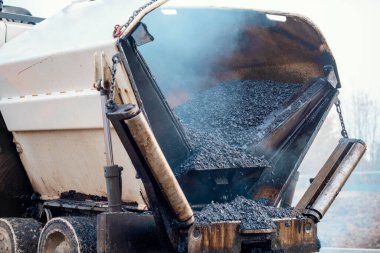 Sıcak asfalt kaldırım taşı yeni yerleşim alanı üzerine yeni yol yüzeyi döşeyen ve yanında turuncu hi-viz 'deki yol işçisi operatörü