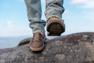 Özel botlu bir adam dağlarda yürüyor. Varış noktasına ulaşıyor. Güneşli bir günde mavi bulutlu gökyüzüne karşı Peak District dağının zirvesinde.