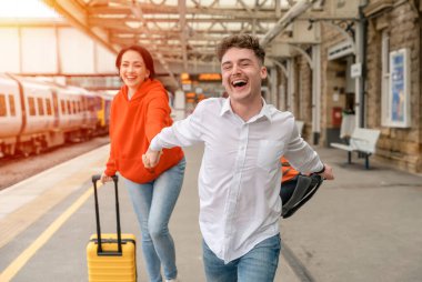 Tren istasyonunda tren bekleyen güzel bir çift. Kadın ve erkek trene binmek için koşuyorlar.