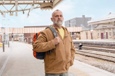 Traveler with a backpack waiting for a train at the train station.   Travel concept.