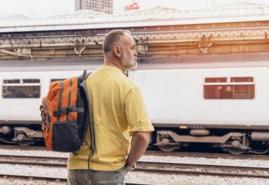 Traveler with a backpack waiting for a train at the train station.   Travel concept.