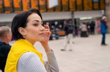 Sırt çantalı ve elinde akıllı bir telefonla tren istasyonunda bekleyen bir kadın. Seyahat kavramının tadını çıkar