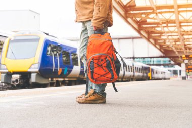 Traveler with a backpack waiting for a train at the train station.   Travel concept.