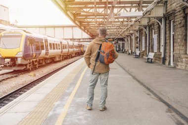 Traveler with a backpack waiting for a train at the train station.   Travel concept.