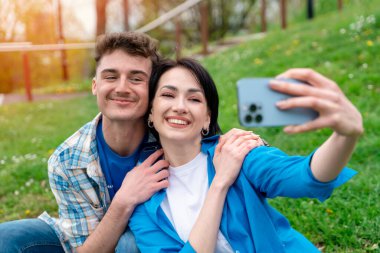 Gülümseyen genç çift akıllı telefondan selfie çekiyor.