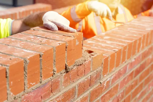 Bricklayers laying bricks on mortar