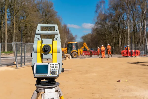 Yellow equipment set out on tripod on building site against cloudless blue sky. Construction site surveying engineering equipment, EDM, tacheometer set out on tripod site ready for setting out.