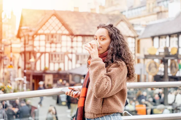 young woman in jacket and orange scarf drinking a coffee,   Lifestyle photo and meeting  friends in a Europe city