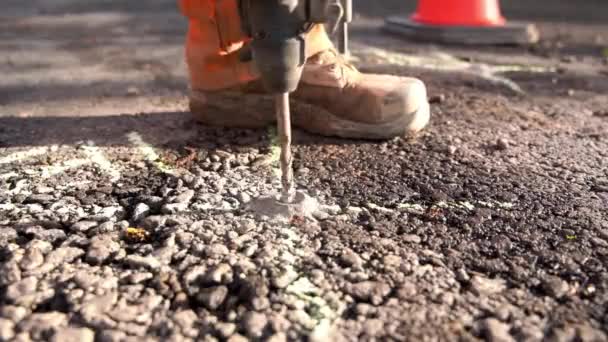 在地盘工程师测量师所标示的位置 使用无绳锤钻在道路上钻孔的建筑商的近照 — 图库视频影像