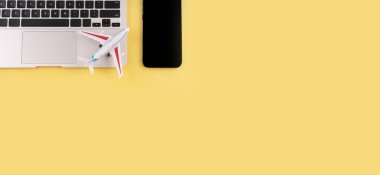 Seyahat et. Laptop, telefon, sarı arka planda fotokopi alanı olan uçak. Yaz tatili konsepti planlıyorum. Yaz çalışma alanı.