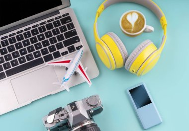 Seyahat et. Laptop, kulaklıklar, mp3 çalar, kamera, uçak ve kahve yeşil arka planda fotokopi alanı ile. Yaz tatili konsepti planlıyorum. Yaz çalışma alanı.