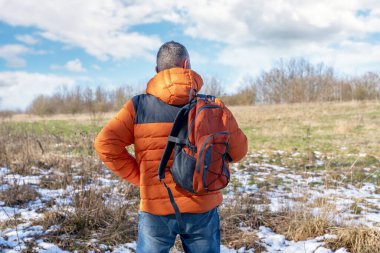 Turuncu ceketli sakallı bir adam kırsalda tek başına dinleniyor. Seyahat yaşam tarzı konsepti. Yerel gezi.