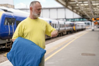 Elinde bavul ve takım elbisesi olan gezgin tren istasyonunda tren bekliyor. Seyahat kavramı.