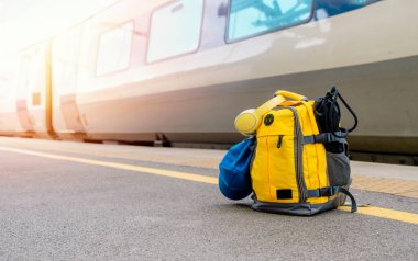 Sarı çantalı, kulaklık takan ve tren istasyonundaki platformda duran. Seyahat konsepti. hafif seyahat