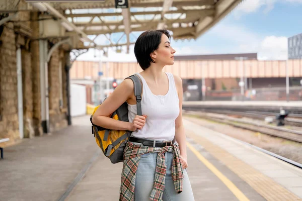 woman with backpack  while at the train station and the train is arriving., Enjoying travel concept