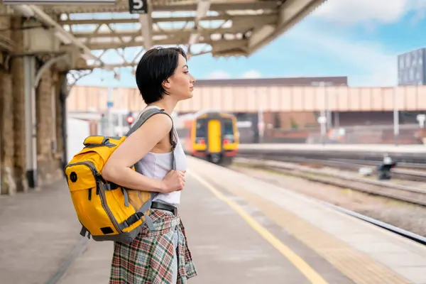 woman with backpack at the train station and the train is arriving., Enjoying travel concept