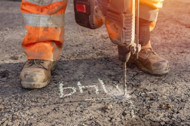 İnşaatçının kablosuz çekiç matkabını kullanarak inşaat mühendisi tarafından işaretlenen yerde delikler açmak için yakın plan.