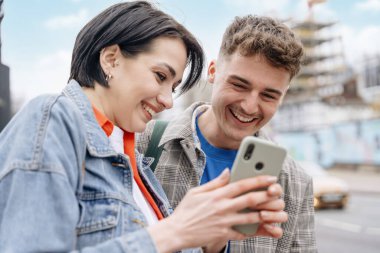 İki arkadaş, telefon kullanan bir çift, selfie çekiyor, fotoğraf izliyor, şehirde eğleniyor. Yaşam tarzı kavramı