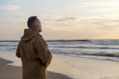Sakallı Adam gün batımında sıcak güneşli bir günde deniz kenarında tek başına dinleniyor. Seyahat yaşam tarzı konsepti
