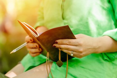 Kadının elinde klasik bir defter var.