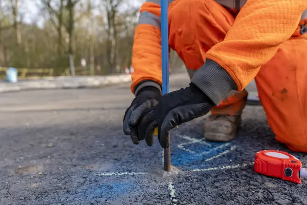 Bir yol geliştirme projesinde çelik çivileri sarı bantla döşeyen inşaatçı yolun bitiş seviyesini işaretliyor