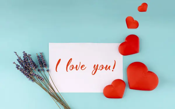 Red  heart on white paper with writing I love you and lavender flowers on green background. Greeting and romantic conceptions