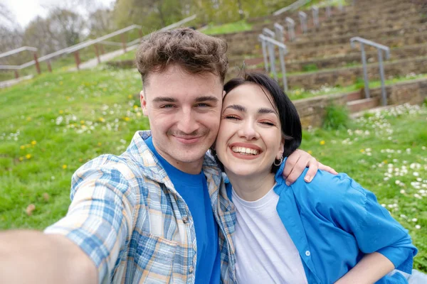 Gülümseyen genç çift akıllı telefondan selfie çekiyor.