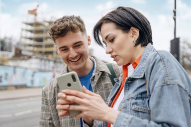 İki arkadaş, telefon kullanan bir çift, selfie çekiyor, fotoğraf izliyor, şehirde eğleniyor. Yaşam tarzı kavramı