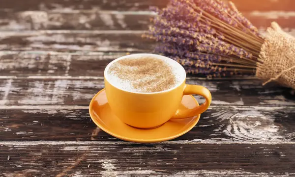 yellow latte coffee cup and lavender bouquet on wooden background