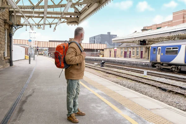 Elinde bavul ve takım elbisesi olan gezgin tren istasyonunda tren bekliyor. Seyahat kavramı.