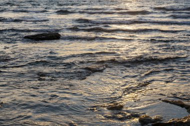 Yazın kayalık sahilde güzel bir gün batımı
