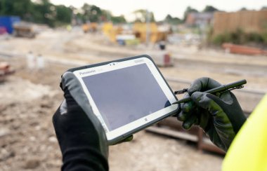 Site mühendisi EDM toplam istasyonunu çalıştırmak için engebeli tablet kontrol bilgisayarı kullanıyor.