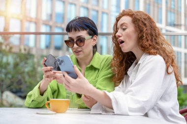 Gülümseyen genç bayan kız arkadaşlar birlikte eğleniyorlar, konuşuyorlar ve şehir dışında telefonlar kullanıyorlar. insanlar, iletişim, arkadaşlık ve yaşam tarzı kavramı