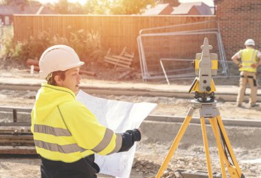 Bir inşaat şantiyesinde Theodolite toplam istasyon EDM ekipmanıyla çalışan kadın inşaat mühendisi araştırmacısı.