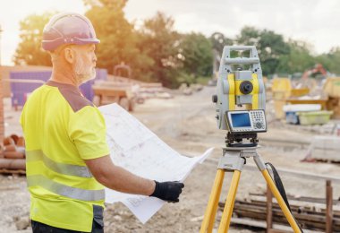 Bir inşaat şantiyesi inşaatında Theodolite toplam EDM ekipmanlarıyla çalışan bir inşaat mühendisi.