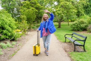 Halk parkında mavi ceketli Asyalı bir kadın yürüyor. Yaşam tarzı yerel turizm ve dinlenme kavramları