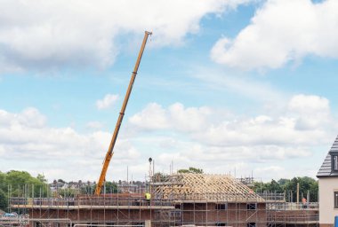 İnşaat alanındaki mobil vinç yeni çatı inşaatı için kirişi kaldırıyor