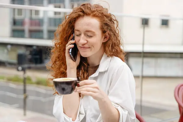 woman having coffee at the street cafe outside, talking on the phone and  having fun time. lifestyle concept