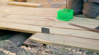 Erkek müteahhit kerestenin vidalarını sökmek için matkap kullanıyor.