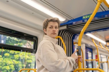 Beyaz ceketli üzgün bir kadının portresi otobüste telefonla konuşuyor.