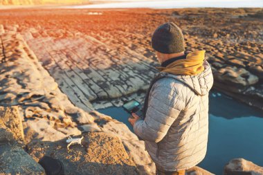 Bearded man using a drone with remote controller  making photos and videos,  having fun with new  technology trends